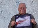 Al Ward, W5LUA, holds his WAS certificate in front of his 5-meter dish. [Photo courtesy of W5LUA]