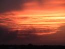Dust and clouds lit by burning wheat fields at sunset