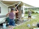 Andrew Templeton (KC0UPF) and Glen Felt (WT0A) work together to raise the awning on the camper to provide some shade for operations. BJ Fictum 6-24-06