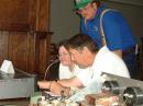 Ron -- KG4QIV helps Linda (Roy's XYL) set up the GOTA station. Roy -- KI4MCX (standing) hopes she will catch "Ham fever".